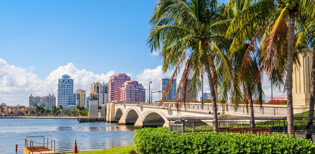  West Palm Beach with landscaping plants, coconut trees, a bridge and buildings.