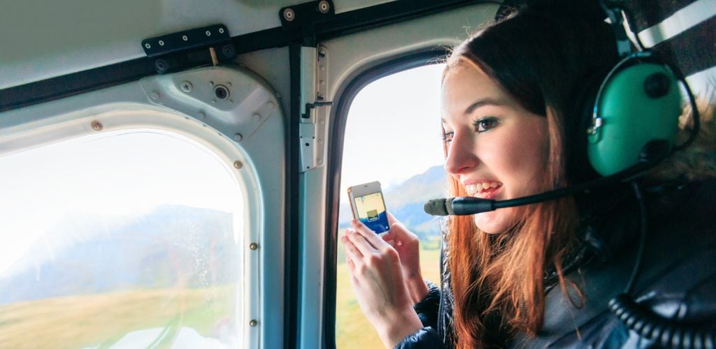 A girl in a helicopter holding a cellphone.