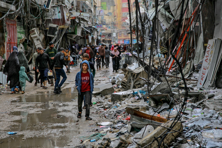 Palestinians walk amid debris near Al-Zawiya market in Gaza City on Nov, 27, 2023.