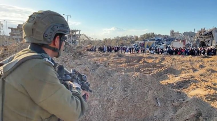 An Israeli soldier watches as Palestinian families flee south on the edge of Gaza City on Nov. 15, 2023.