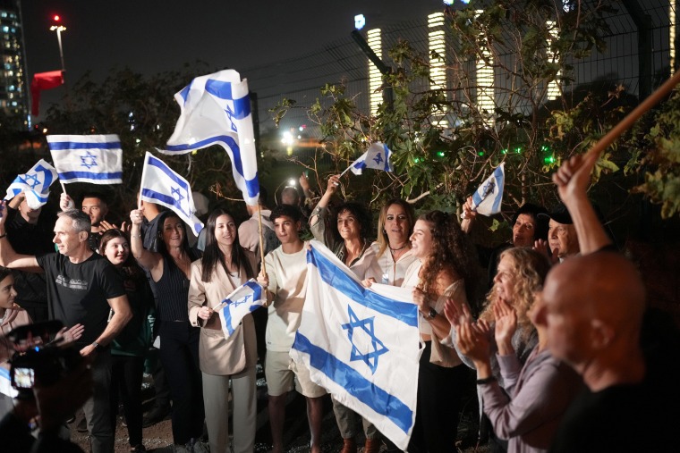 People wave Israeli flags as hostages arrive at the Schneider medical centre by helicopter.