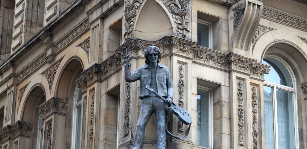 Statue of John Lennon on the Hard Day's Night Hotel holding a guitar and wearing a sunglasses and hand in peace sign. 