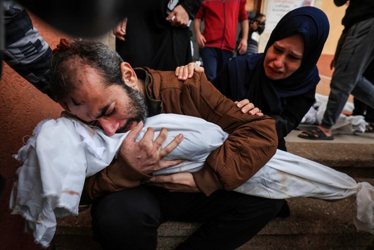 Jamil al-Agha and his wife cry as he holds the body of one of their two children killed in Israeli bombardment in Khan Younis, Gaza.