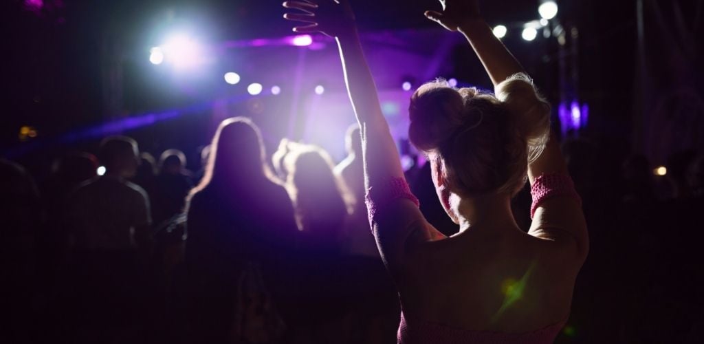 A woman standing at the crowded club and enjoying.