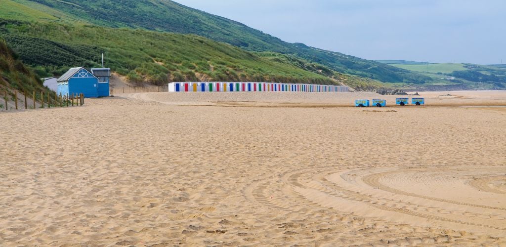 Woolacombe beach in the morning. Woolacombe is a seaside resort on the coast of North Devon, England, which lies at the mouth of a valley in the parish of Mortehoe. The beach is 3 miles (4.8 km) long,
sandy, gently sloping and faces the Atlantic Ocean 