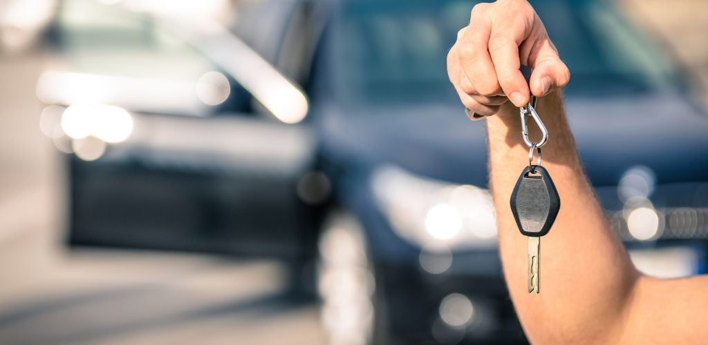 Man's Hand Holding Modern Car Keys Ready for Rental. 