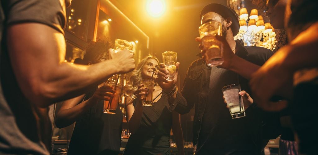 Group of friends having drinks at-bat together. Young people at a nightclub enjoying cocktails. 