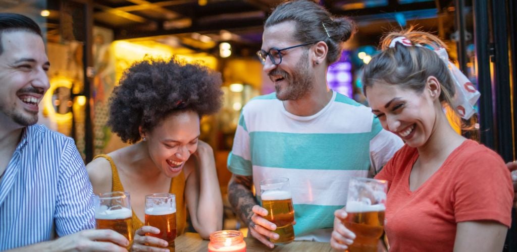 Group of young cheerful people having fun drinking beer outdoors.