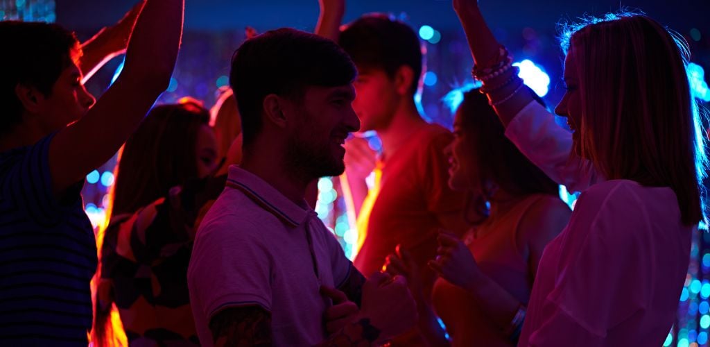 A group of young adults dancing on the dance floor. 