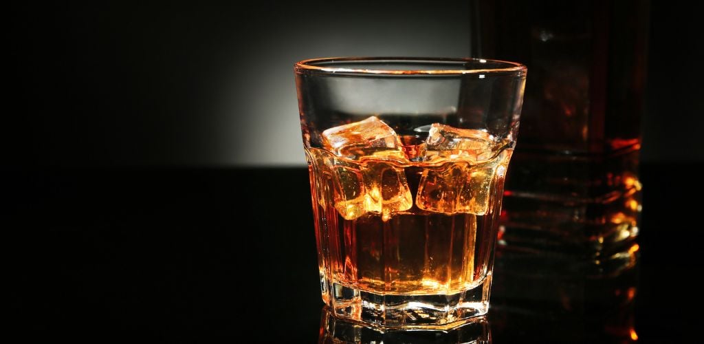 Glass of Whisky on dark background.