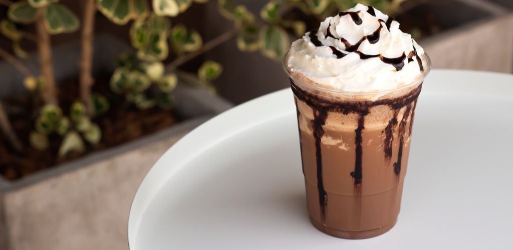 Mocha frappe in plastic cup. Served with whipping cream and chocolate sauce.