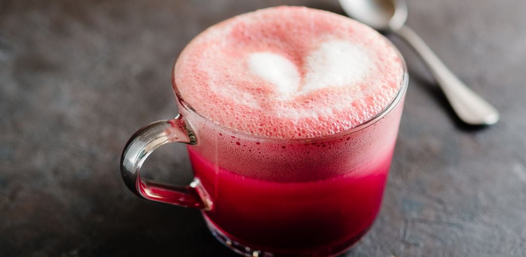Pink Beetroot Latte or Red Velvet Latte in a glass or cup and a spoon on the background. 