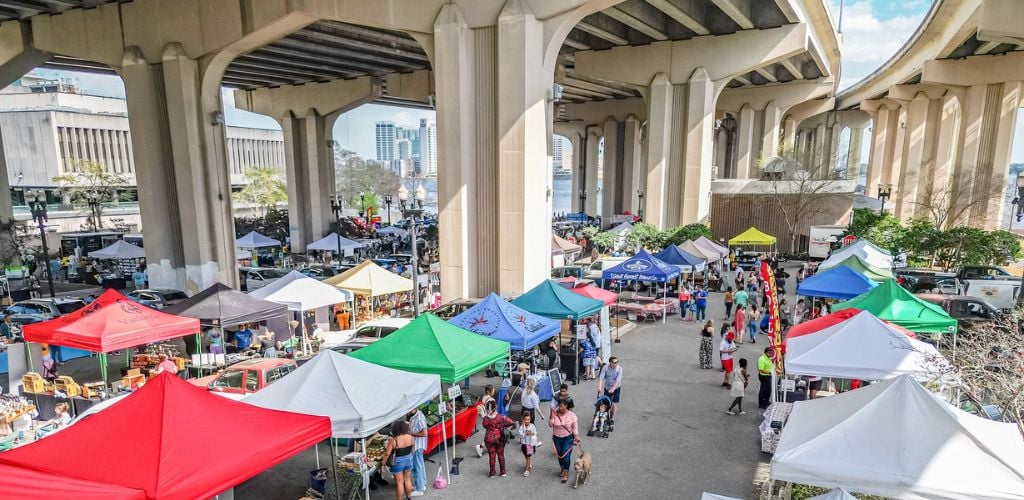 A local market under the bridge and customers walking around. 