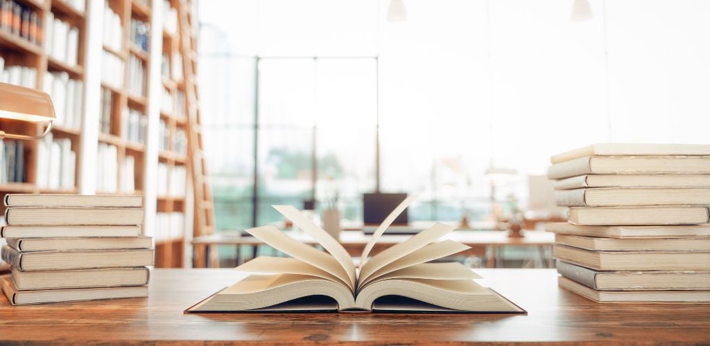 Old books on the wooden desk in a library. 