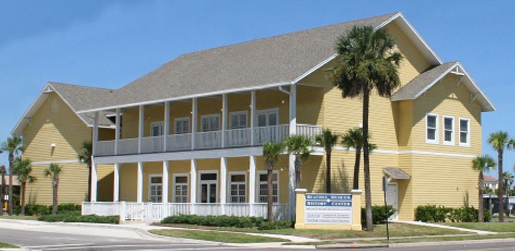 Beaches Museum house in yellow with a tree on the side corners. 