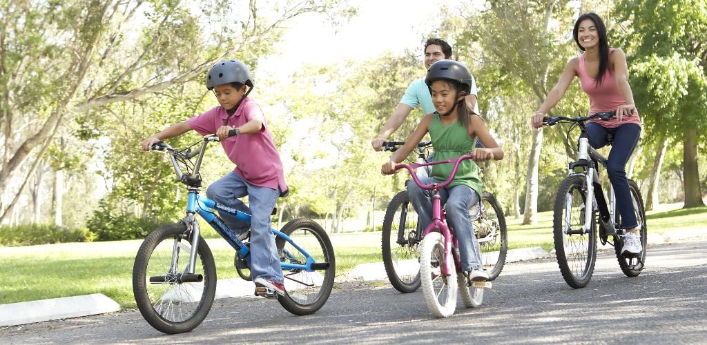 Young Family Riding Bikes in Park