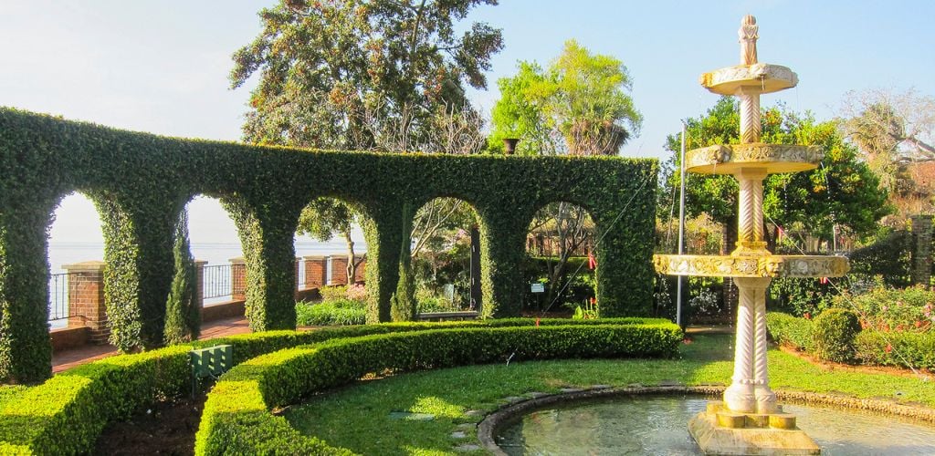 A garden with arched walls and a fountain 