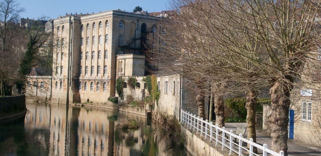 A canal, as well as an old building with trees on the side