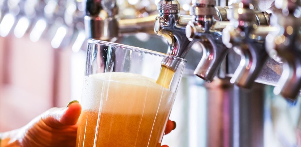 The bartender pouring draft beer in the bar. 