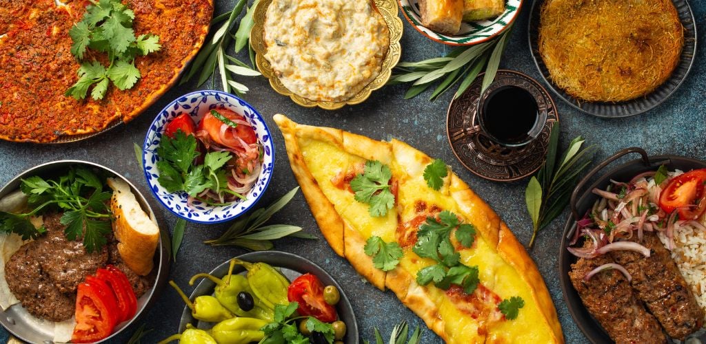 Traditional Turkish food, assorted dishes, and mezze appetizer on rustic background from above. Pide, Lahmacun, meat kebab, Turkish meatballs, sweet baklava, and Kunefe. Middle East cuisine, top view. 