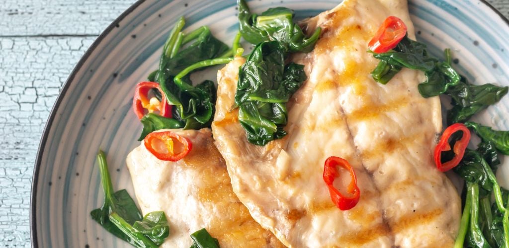 Grilled sea bream fish fillet with spinach and chili pepper. 