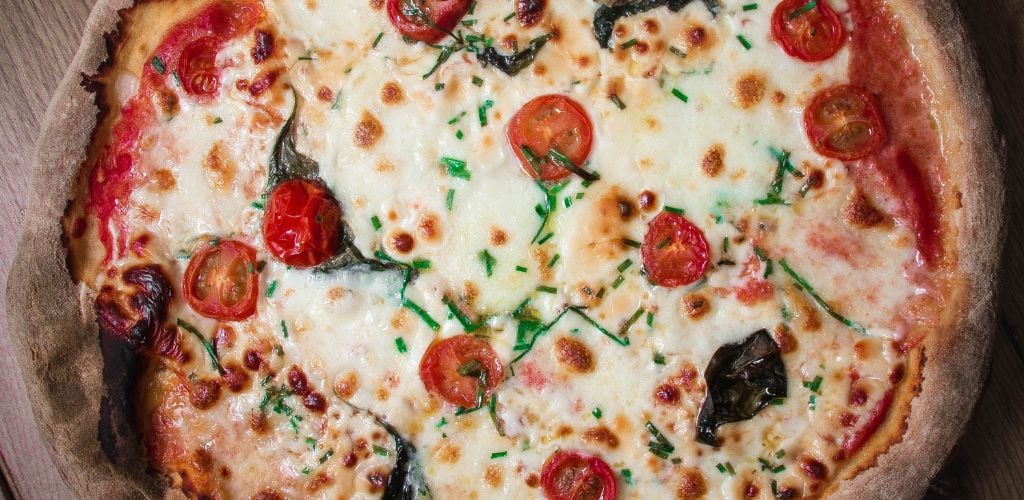 New York-style pizza, with fresh mozzarella, sliced mozzarella, and cherry tomato. 