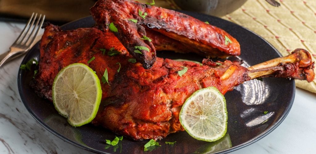 Indian cuisine spicy red Tandoori chicken with cucumber raita. 