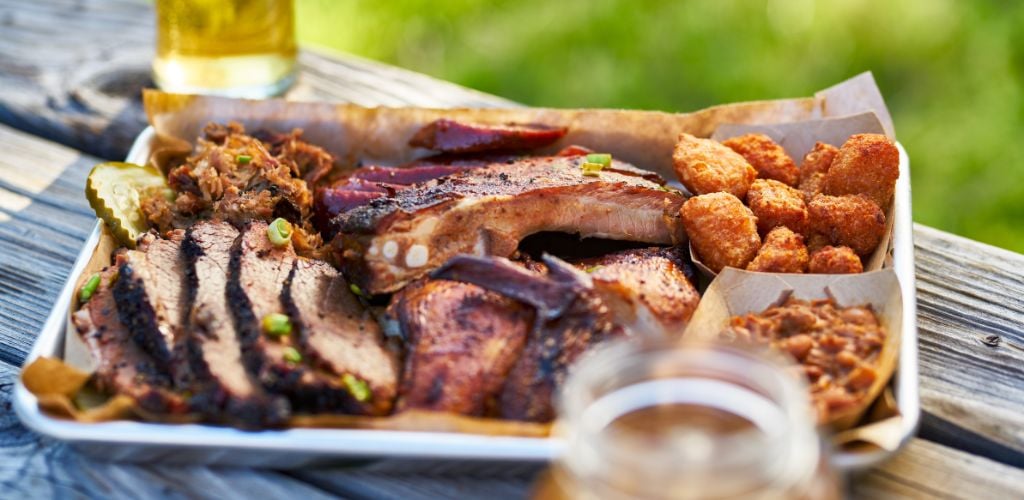 Tray of Smoked Meats Bbq Style outside wooden table on Sunny Summer Day