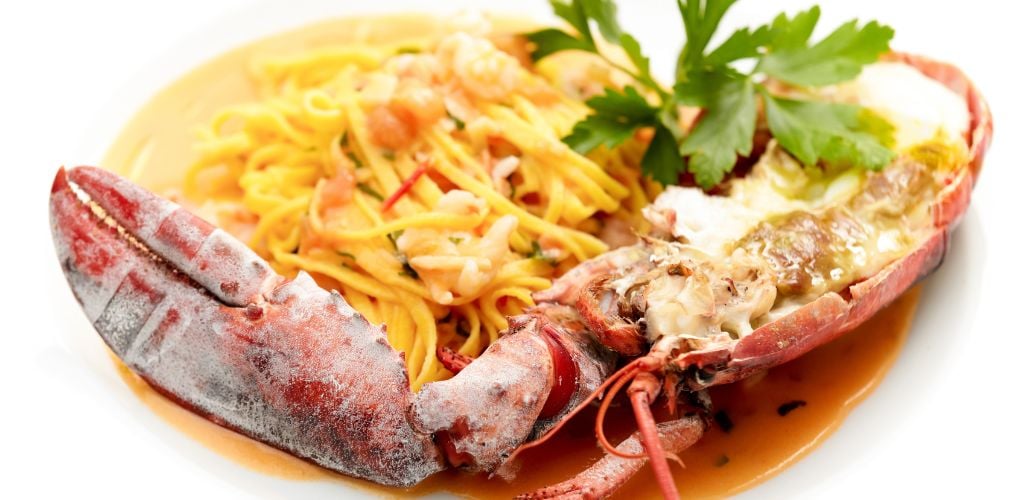 A pasta with lobster served on a white plate.