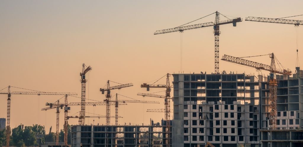 Construction of a residential building on a summer evening. Many cranes are in operation. 