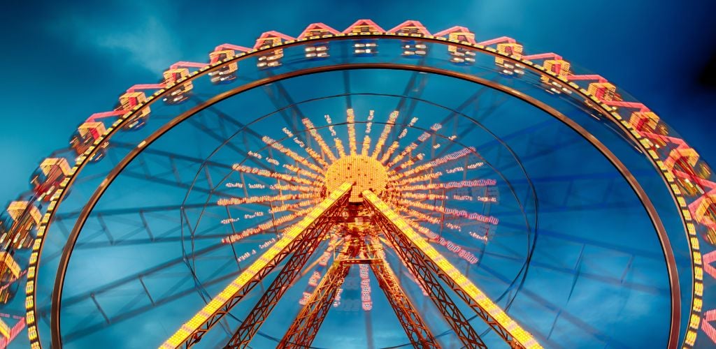 In the night sky, a Ferris wheel with a magnificent light on it.