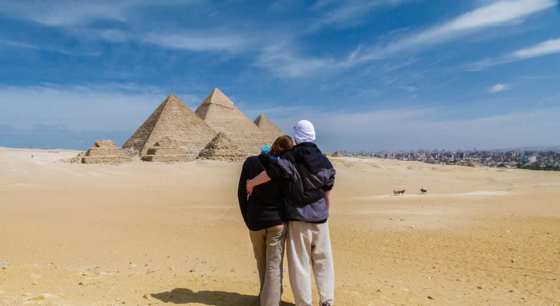 Dariece and Nick looking at the pyramids of Giza in Egypt. A view from behind them.