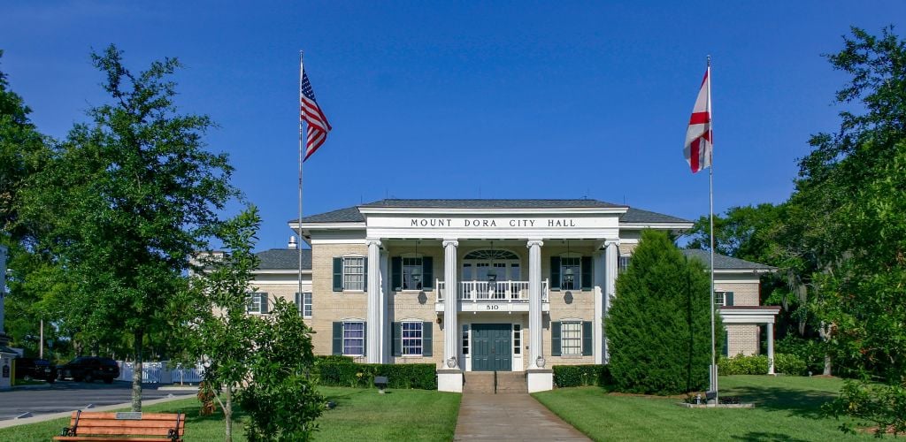 Mount Dora, Florida City Hall and Landscaped Grounds with State and US Flags flying under a clear blue sky 