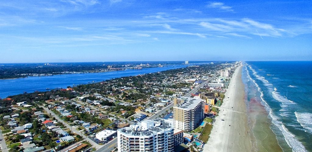 Aerial view of Daytona Beach, there a building structures surrounded by sea and blue clear sky. 