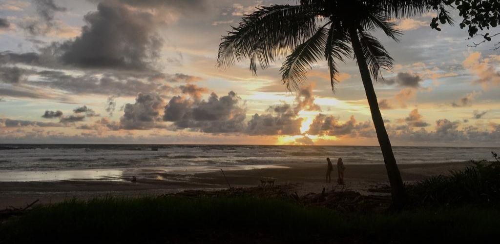 Two people are standing and admiring the sunset over the beach. 