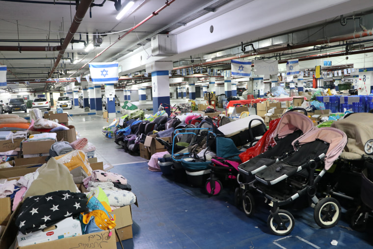 Strollers and other donated items fill a parking lot under the Expo Tel Aviv convention center. 