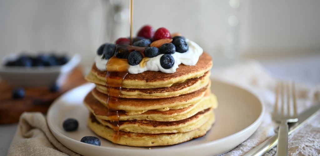 Pancakes with blue berry, strawberry, almonds and Whipped Cream.