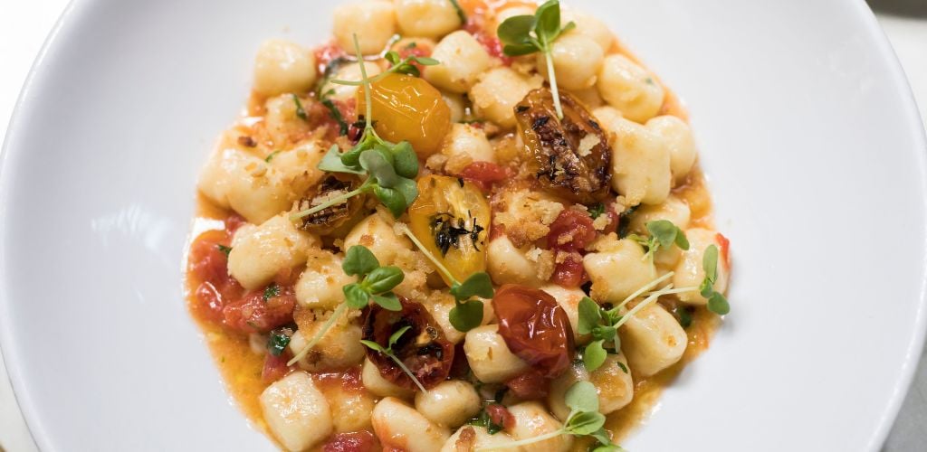 Tasty gnocchi with tomatoes and herbs on plate