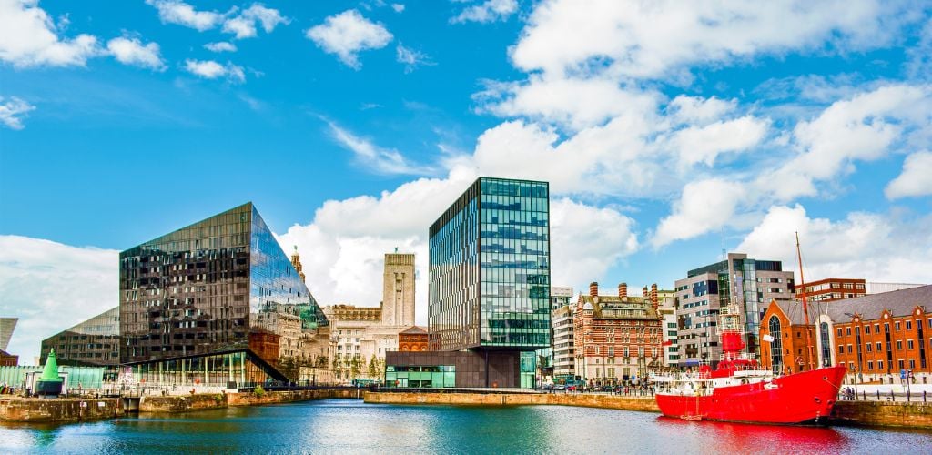 Buildings near the Mersey in Liverpool, England. A Red boat docked on the side river. 