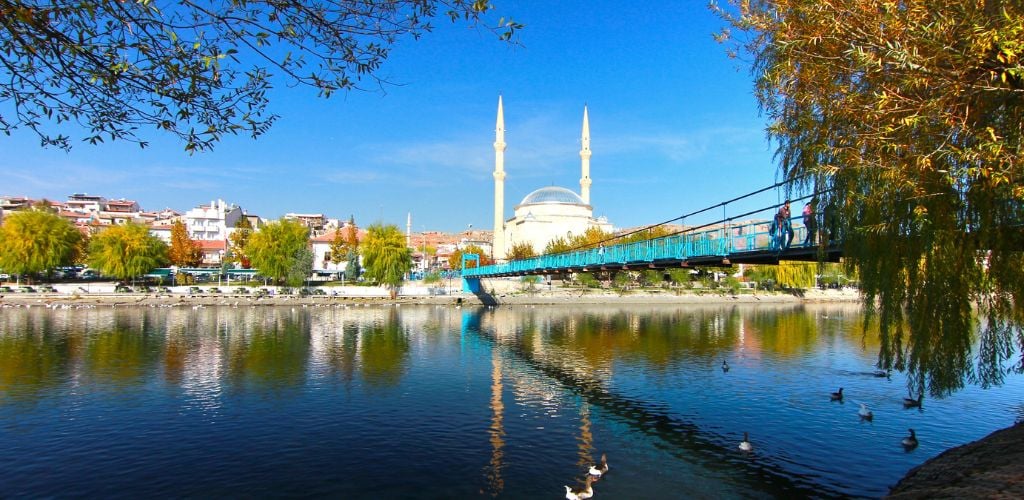 A lake, a bridge, and a massive structure with two towers on opposite sides, resembling a dome. 