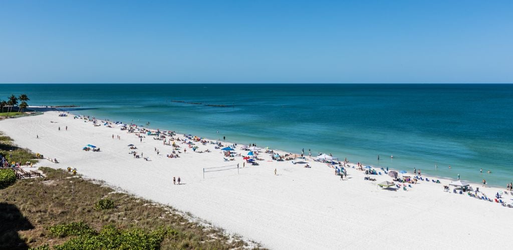 Blue sky and white sand in Marco Island, South Beach, Florida. There are a lot of tourists on the beach. 