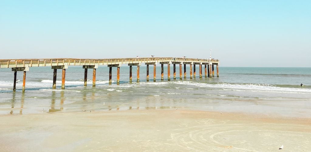 A pier leading to the sea, with clean and clear water. 