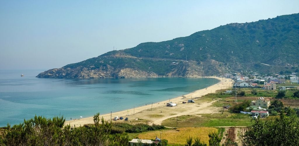 A top view of the beach and landscape, with a green mountain in the distance. 