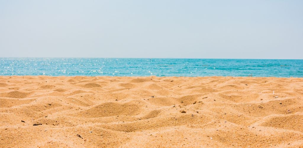 Sandy beach and a blue clear sea in the background. 