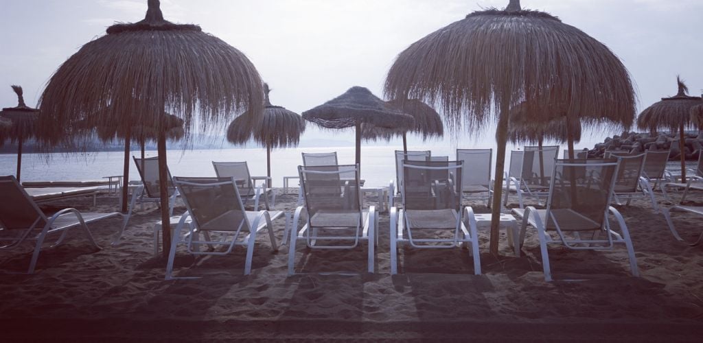 A beach umbrella made of dried coconut leaves and a beach chair