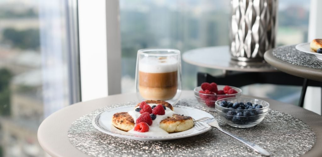 Cup of latte and cottage cheese pancakes with blueberries and raspberries.