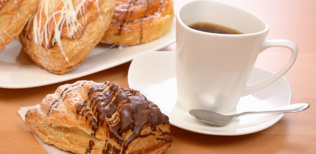 Cup of black coffee and pastry on a counter top. 