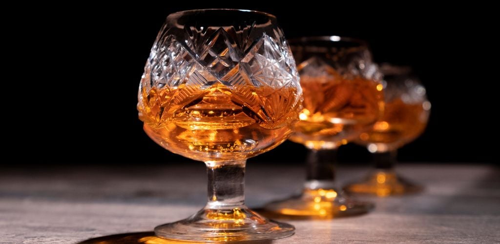 Close-Up of three glasses of whiskey on the table with black black background. 