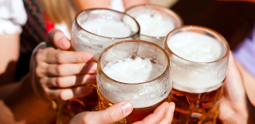A close-up shot of four friends toasting a fresh beer. 