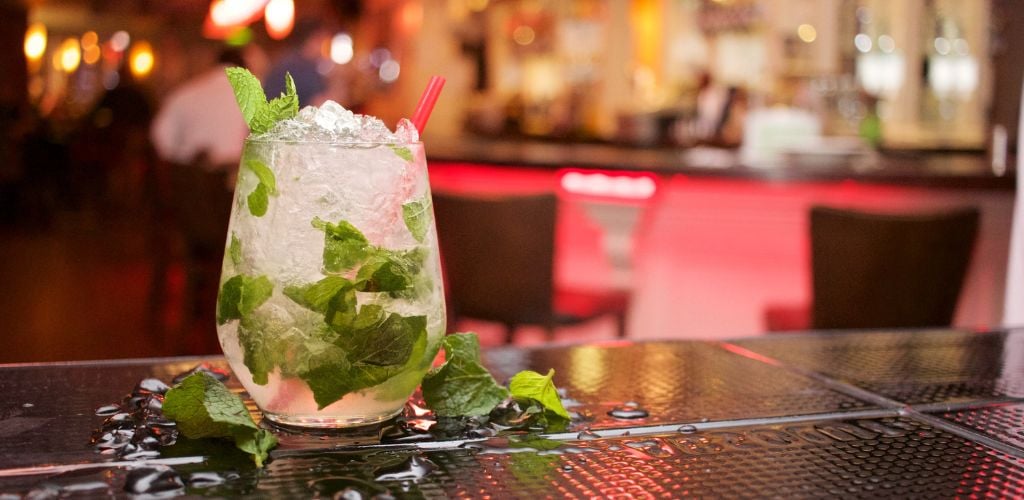 A refreshing Mojito Drink is served at the bar on a black table. 